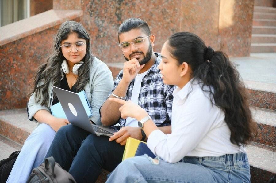 Students preparing for NAATI CCL and PTE exams, studying together with laptop and books
